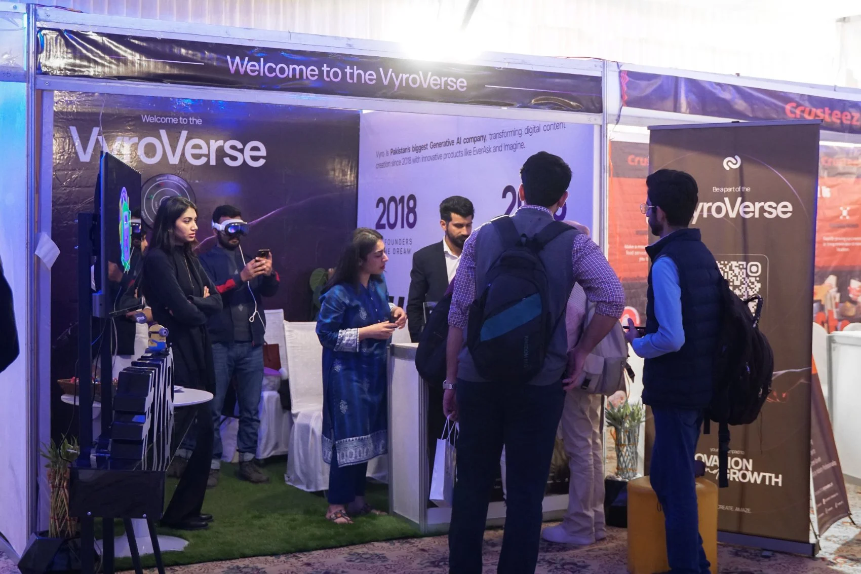 Vyro career fair booth in use, visitors trying a headset under the Welcome to the VyroVerse backdrop