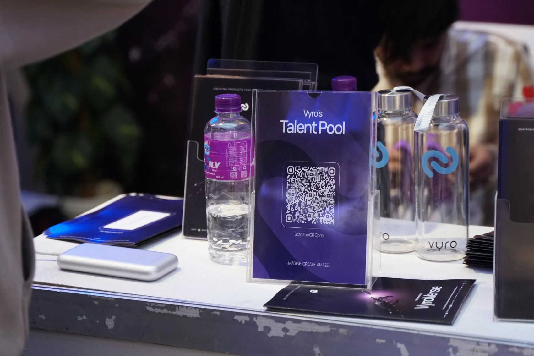 Booth counter with the Talent Pool QR card, brochures and branded bottles