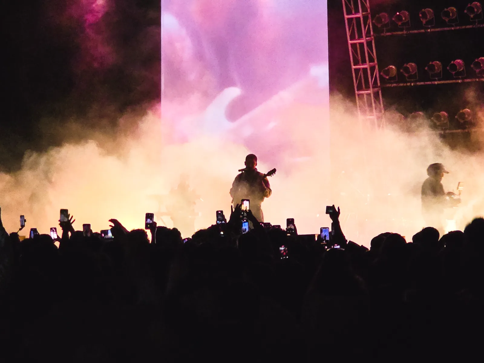 Concert crowd silhouetted in smoke and stage light