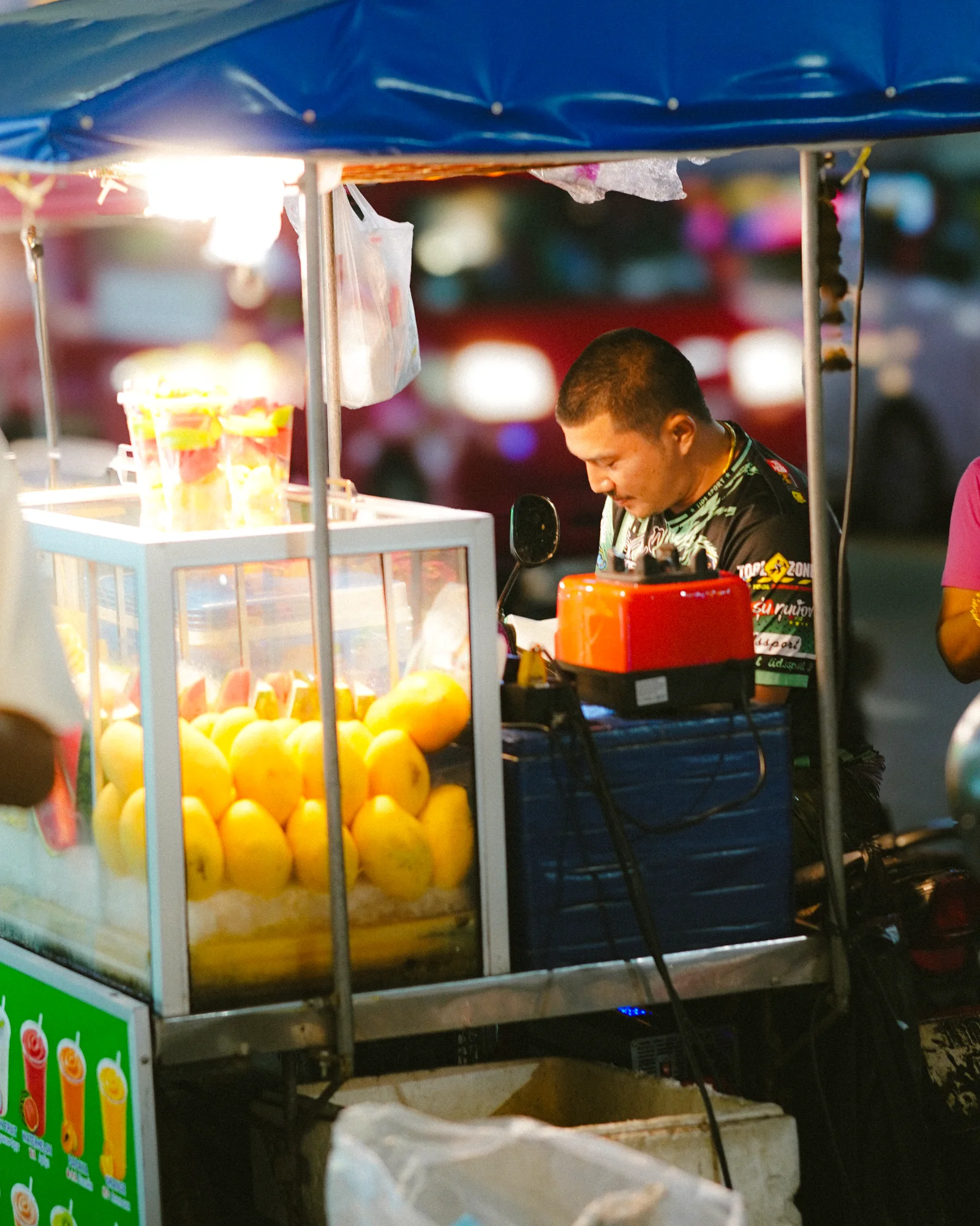 Night fruit stall lit under a blue canopy