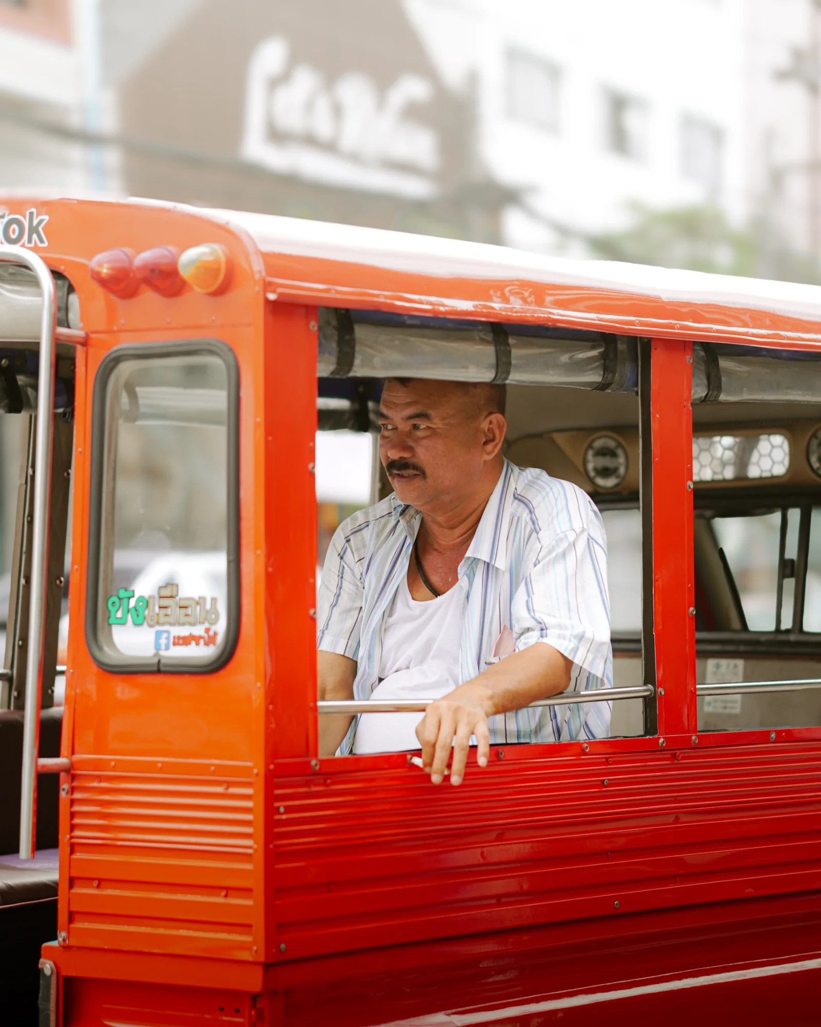 Driver waiting in an orange tuk-tuk